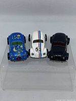 Front view of three Volkswagen Beetle Hot Wheels cars on display stand