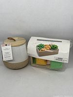 Citronella candle in ceramic jar with wooden lid and attached product tag visible. DIY succulent planter kit packaging and materials also shown.
