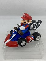 Mario figure in blue and red kart, front right angle view showing wheel, steering, and figure details.