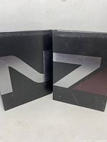 Two black game discs with silver N7 logo on top, lying open inside case.