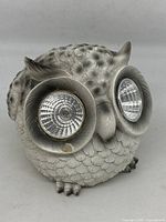 Front view of gray textured owl-shaped solar light with light fixtures in eye sockets.