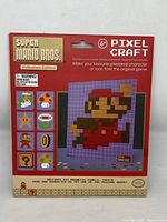 Front of original Super Mario Bros Pixel Craft box showing pixelated Mario and grid design graphics with characters and icons from the game.