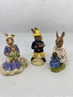 Photo of three Royal Doulton Bunnykins figurines from 1972, 1988, and 2004 positioned side by side showing front detail.