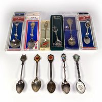 All 11 vintage souvenir collector spoons arranged in 2 rows, some in original packaging including Moscow, Newfoundland, Canada, Cuba, Quebec, Florida, Plymouth Rock, San Diego, San Francisco, California.