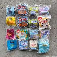Overview of all 20 McDonald's vintage Happy Meal toys sealed in original bags, arranged in a grid on a gray surface.