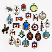 Photo of 24 assorted vintage sterling silver Canada themed dangle bracelet charms, colorfully enamelled, laid flat along with a ruler for scale.
