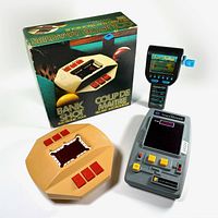 Photo showing 3 handheld electronic games: Bank Shot with box and manual, Space Invader, and Fun Fishin handhelds. Various buttons and display screens visible.