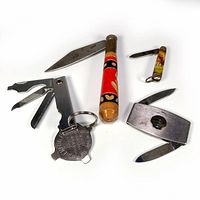 Overview of all four items in the lot showing the Shell gasoline advertising knife, wood-handled folding knife, RCMP souvenir knife, and multi-tool keychain with screwdriver