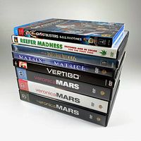 Stack of 8 DVDs and Blu-Rays showing titles: Ghostbusters Answer the Call (Blu-Ray), Reefer Madness, Into the Woods (sealed), The Matrix, Vertigo, and three Veronica Mars season DVDs.