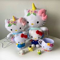 Collection of all 8 items including 2 large Hello Kitty unicorn plushes, smaller Hello Kitty plush, night light, mug, and 3 small vinyl Sanrio figures