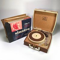 Photo of RCA Victor K-679 portable phonograph in open suitcase case with 38 shellac records beside it including Sinatra album covers.