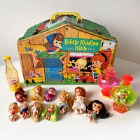 Overview of carry case, track insert, bottles and assortment of dolls laid out on surface