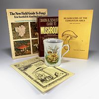 Five mushroom-themed items: two large vintage mushroom field guides, two smaller pamphlets, and a ceramic coffee mug decorated with chanterelle mushrooms.