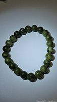 Photo of natural green jade bead bracelet with round beads approximately 8mm diameter on white background.