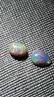 Natural AAA Ethiopian black opal pear and oval cabochons displayed under lighting to show multicolor play.