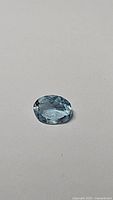 Close-up top view of 2ct natural oval cut aquamarine with visible facets and blue color.