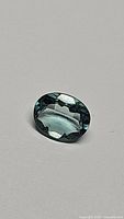 Photo of oval cut natural fluorite gemstone showing paraiba blue-green color under normal lighting
