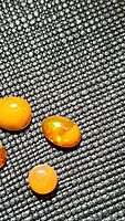 Close-up of three polished fire opal cabochon gemstones on a black textured surface showing vivid orange color and internal play-of-color.