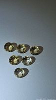 Seven natural golden citrine oval faceted gemstones arranged on a neutral background showing their clarity and color.