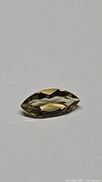 Close-up image of natural golden citrine gemstone, marquis cut shape on neutral background.