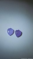 Two natural lavender jade gemstones of matching size and shape, carved in fancy spade cuts, shown on a white background under bright light to highlight color and translucency.
