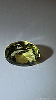 Photo of oval cut lemon citrine gemstone showing facets and color in natural lighting.