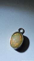 Close-up of oval-shaped Ethiopian opal pendant set in silver bezel showing vibrant color flashes and patina on silver