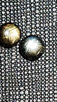 Close-up photo of pair of natural black star sapphires on textured dark fabric showing star effects and surface details.