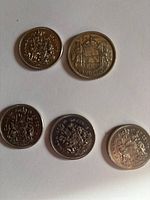 Photo of reverses (coat of arms) of five Canadian half dollar coins dated 1956, 1971, 1974 (two coins), and 1975.