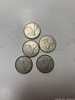 Front side of five 1968 Canadian silver quarter coins showing the caribou design.