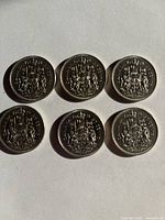 Reverse sides of six Canadian 50 cent coins showing the Canadian coat of arms.