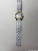 Front view of Betsey Johnson watch showing colorful numeral design and white quilted strap.