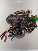 Photo showing assorted bracelets, colorful beaded necklaces, earrings, and decorative brooches piled together.