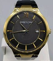 Front view of Kenneth Cole men's wristwatch showing textured black dial, gold-tone numerals, and date window.