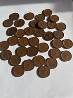 Photo showing 36 Canadian pennies from 1967 arranged on a white surface, each featuring the centennial maple leaf design.