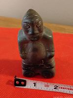 Front view of the Inuit stone carving figurine with measuring tape showing width just under 2 inches.
