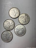 Top view of five Canadian silver quarters showing the caribou side dated 1958, 1959, 1960, 1962, and an unclear date.