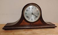 Front view of vintage Sessions mantle clock showing wooden case and silver face with Arabic numerals.