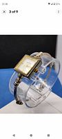 Side angle of Anne Klein women's wristwatch showing square gold tone bezel and bangle bracelet.