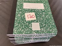 Top view of stacked green marble cover quad ruled notebooks showing label and quantity.