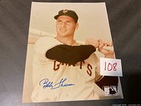 Signed color photograph of Bobby Thomson in a New York Giants baseball uniform holding a bat, showing signature and official Cooper Baseball logo.