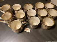 Set of 13 ceramic mugs arranged in two rows, showing tops and side views.