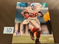 Photo of a signed 8x10 photo featuring DJ Ware running with football in New York Giants uniform, with autograph in blue ink on left side.