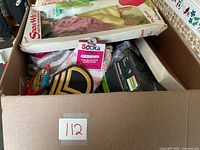 Top view of the open cardboard box showing its contents including boxed doll, socks, headwraps and patch