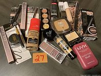 Photo of unopened makeup products including foundations, concealers, powders, eyeshadows, and blushes.