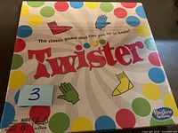 Front view of unopened Twister board game box with shrink wrap intact, colorful dots, and Hasbro Gaming logo.