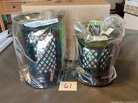 Two Forever Fragrant ceramic fragrance lanterns wrapped in plastic, showing lattice pattern and wide openings, sitting on a table with a cardboard box in the background.