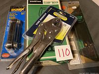 Overall view of the tools lot showing vise wrench, clamp meter in box, hex key set, and levels.