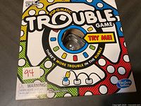 Photo of the Trouble game box showing the Pop-O-Matic bubble die roller and colorful game artwork with warning label and age recommendation.