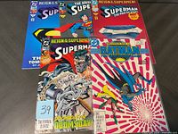 Photo showing six comic books arranged in two rows, featuring Superman and Batman titles including Reign of the Superman and Batman: The New Adventures.